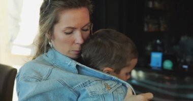 Genç zarif anne soğuk sonbahar gününde ısınmak için beş yaşındaki oğlunu cekete sardı. Ebeveynler ve küçük çocuklar arasındaki şefkat ve bakım anları. 4k görüntü.