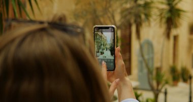 Arka plan kadını kamera uygulamasında ekranda telefon düğmesine bas. Kadının yakından çekilmiş fotoğrafı. Akıllı telefon uygulaması kullanarak egzotik caddenin fotoğrafını çekiyor. Yüksek kalite fotoğraf