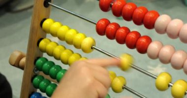 Kreşte Abaküs 'ün renkli toplarının yerini akıllı çocuk parmağı alıyor. Yakın plan çekimde. Küçük çocuk matematiği klasik sayma cihazıyla öğreniyor.