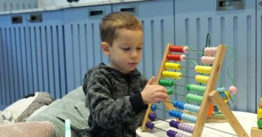Zeki çocuk anaokulunda renkli ahşap abaküse güveniyor. Küçük çocuk kreşte oyuncakla matematik öğreniyor. Çocuk gelişimi