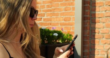 Telefonda sosyal medyada tişört giymiş şık bir kadın. İş kadını gelen mektupları çağdaş cep telefonu kullanarak gözden geçiriyor