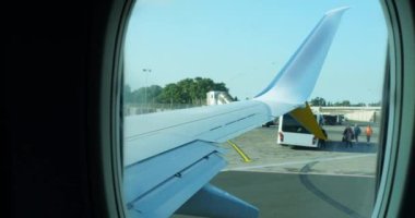 Güneşli bir gün ışığında salonun penceresinden yolcu uçağının pist boyunca sürüşü. Modern ticari uçakla iyi yolculuklar. Uluslararası havaalanı