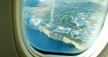 Uluslararası havaalanı, ticari uçağın penceresinden ada manzaralı. Uçan jetten tatil köyündeki kadın yolcu parmakla işaret ediliyor. Seyahat hobisi