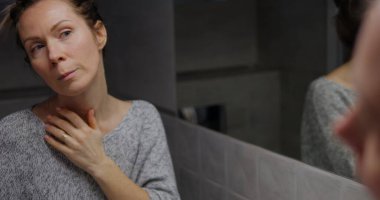 Kendine güvenen genç bir kadın eğilip aynaya bakar ve kaş makyajını kontrol eder. Kendini beğenmiş kadın kafasının arka planı ve banyoda yansıyan yüz. Yüksek kalite fotoğraf