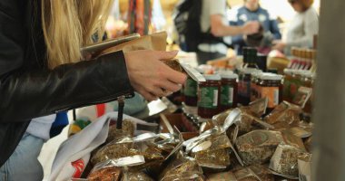 Deri ceketli genç bayan öğrenci yerel pazarda yiyecek baharatı seçiyor. Tanınmayan turist kadın, özgün ev yapımı Malta malını hatıra ya da hediye olarak seçiyor..