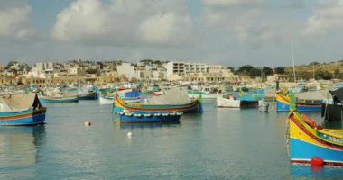 Marsaxlokk, Malta - 1 Mayıs 2023 - Marsaxlokk Körfezi 'nin panorama çekimi farklı renkli parlak teknelerle. Ünlü resimli Malta balıkçı köyü deniz bölgesi.