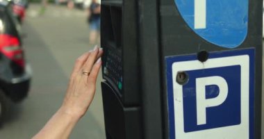 Park metre tuşundaki zarif kadın el tipi plaka numarası. Tanınmayan bir kadın, güneşli bir yaz gününde açık hava otoparkından park bileti alıyor..