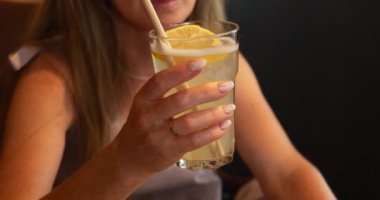 Rahat kadın kulüpte limon dilimi ve samanla tropikal kokteyl gösteriyor. Restoranda taze meyve suyu satan bir bayan var. Sağlıklı içecek.