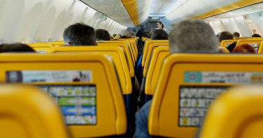 WARsaw, POLAND - 23 Nisan 2023: Ryanair yolcuları yurtdışındaki uçuş sırasında rahat uçak koltuklarında oturuyorlar. İnsanlar yolculuk için güvenli ve hızlı hava ulaşımını seçer. Turistler modern uçakla seyahat ederler.