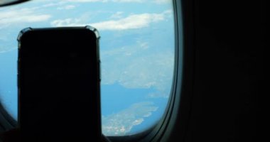 Mavi gökyüzünde, yolcu uçağının camından akıllı telefonla çekilmiş inanılmaz bulutlu bir manzara. Tatilde yurtdışına uçtuğumu hatırlıyorum.