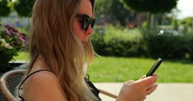 Kadın girişimci akıllı telefon kullanarak çevrimiçi ticaret yapıyor. Çevrimiçi mağazanın sarışın yöneticisi cep telefonu kullanarak müşteri siparişlerini kabul ediyor