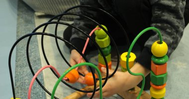 Küçük çocuk yerde renkli telli boncuk labirentiyle oynuyor. Meraklı çocuk anaokulunda top sürat treni eğitimi alıyor. Çocuk gelişimi