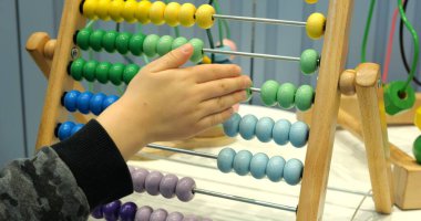 Küçük çocuk anaokulunda abaküs kullanarak parmak eklemlerini hareket ettiriyor. Küçük çocuk matematik öğrenmek için geliştirme oyuncağıyla oynuyor.