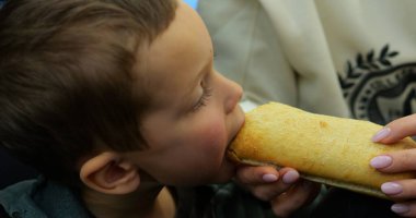 Küçük çocuk uçak kuaföründe oturup ısırıp çiğnerken anne elinde turta tutuyor. Kadın, karnını doyurmak için küçük bir çocuğu kabuklu çörekle besliyor. Yolculukta atıştırmalıklar