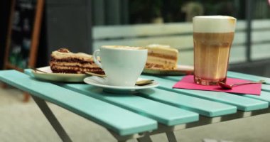 Cafe masasında köpüklü latte ve glütensiz pastalı kremalı kapuçino var. Vejetaryen ya da vejetaryen diyetine uyanlar için hoş bir seçenek