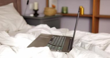 Dairenin yatak odasındaki rahat yatakta bırakılan dizüstü bilgisayar serbest çalışanların esnek programını simgeliyor. Serbest meslek, uygun çalışma alanını seçmede özgürlük sunar