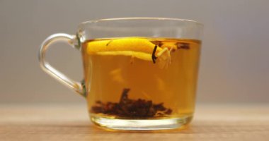 Şeffaf bardak bitkisel çay ve taze limon dilimi ile dolu tahta masaya koyun. Sabah gevşemesi için zengin bir tat veren Aromatik içecek.