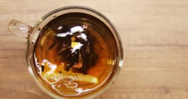 Kişi taze limon dilimini şeffaf siyah çaylı bardağa atar. Doğal ürünler kullanılarak enerjiyi yeniden başlatmak için lezzetli içeceğin hazırlanması