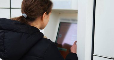 Esmer kadın interaktif paket terminali verilerini dolduruyor. Genç bayan uygun depolama ünitesinin kilidini açmak için paket boyutlarını yazar