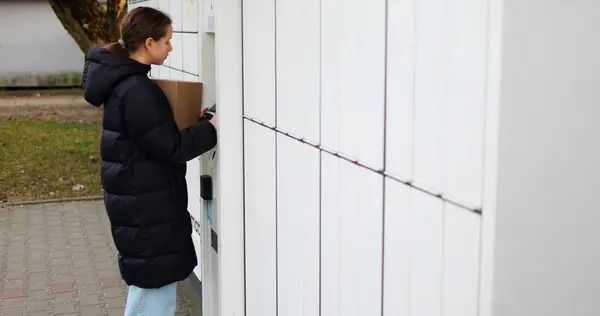 Genç bayan verileri doğrulamak ve uygun dolabın kilidini açmak için terminali bekliyor. Esmer kadın uygun depolama birimine ulaşmayı umuyor.