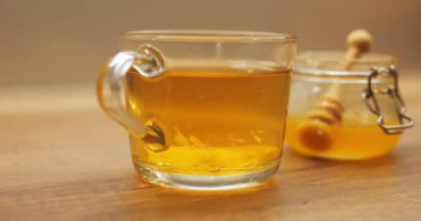 Kavanozdan bal ve şeffaf bardakta dönen limon parçalarıyla demlenmiş sıcak çay. Soğuk akşamlar için narenciye serpiştirilmiş Aromatik içecek.