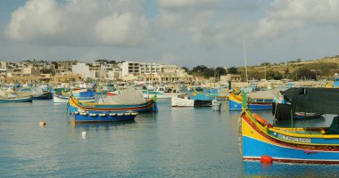 Geleneksel balıkçı tekneleriyle dolu göz kamaştırıcı ve pitoresk bir liman, sakin bir gökyüzünün altında güzelce dinleniyor.