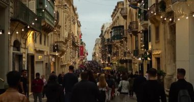 Valletta, Malta - Mayıs 2023 - Ana turistik akşam caddesi aydınlandı. Başkentin merkezinde ışıklarla süslenmiş eski bir kasabada yürüyen turist kalabalığı. Yüksek kalite 4k video