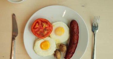 10 Mart 2023, Kafe 'deki masaya sıcak ve tatlı tabaklar konulmuş kahvaltı. Ana yemek olarak yumurtalar servis edilirken soslu krepler ve bir fincan kahve tatlıyı hazırlıyor.