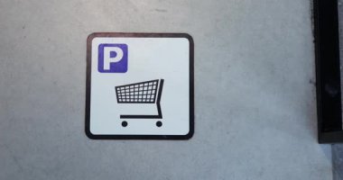 WARsaw, POLAND - 10 Mart 2023: işaretli duvarda kesik çizgiler alışveriş arabaları için park alanı göstermektedir. En üst köşede P sembolü, ortada da alışveriş arabası simgesi var
