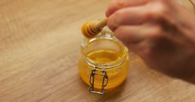Kadınlar şeffaf kavanozdan limonlu çayın tadını zenginleştirmek için bal toplayıcı taşırlar. Limonlu yatıştırıcı içecek, sağlığı desteklerken soğuk belirtileri azaltır.