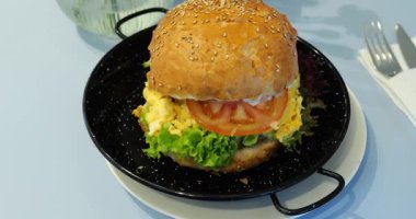 Yağda yumurta, kıtır marul ve domatesli tuzlu burger. Restoran masasındaki çatal bıçaklı susamlı çörekler arasında karşı konulmaz bir yemek.
