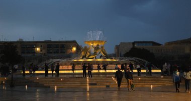 Valletta, Malta - 1 Mayıs 2023 - Akşamları Triton çeşme simgesi aydınlandı. Ana modernist turist eğlencesi betondan yapılmış ve travertin levhalarla kaplanmış.