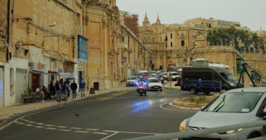 Valletta, Malta - Mayıs 2023 - kavşakta mavi fenerli polis motosikleti. Motosikletli polis memuru el fenerlerini açtı. Eski şehrin bir bölümünde trafik sıkışıklığını izliyorlar..
