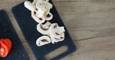 Mutfakta yemek pişirmeden önce tavayla kesme tahtalarının üzerinde yemek için doğranmış malzemeler var. Küçük domatesler ve şampiyonlar yemeğin bir parçası olarak servis edilir.