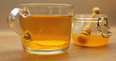 Kavanozdan limon dilimi ve organik bal içeren bir bardak taze demlenmiş çay. Bağışıklık sistemi şarjı için narenciye katılmış sıcak içecek.