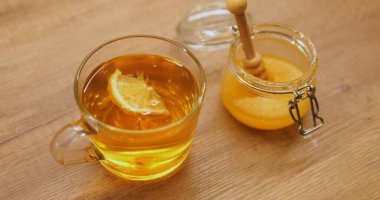 Limon dilimleri masada bal kavanozunun yanına konmuş şeffaf bir fincan çay ile döner. Narenciye ve doğal tatlılık katılmış sıcak içeceği canlandırmak