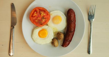 10 Mart 2023, Kafe 'deki masaya sıcak ve tatlı tabaklar konulmuş kahvaltı. Ana yemek olarak yumurtalar servis edilirken soslu krepler ve bir fincan kahve tatlıyı hazırlıyor.