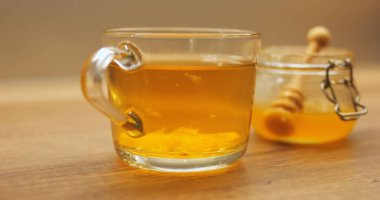 Kavanozdan bal ve şeffaf bardakta dönen limon parçalarıyla demlenmiş sıcak çay. Soğuk akşamlar için narenciye serpiştirilmiş Aromatik içecek.