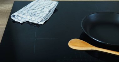 Yemek yapmadan önce taze malzemelerin ve özel ekipmanların hazırlanması. Pişirme işlemi sırasında yemekleri karıştırmak için tava ve kaşık indüksiyon hob yalan