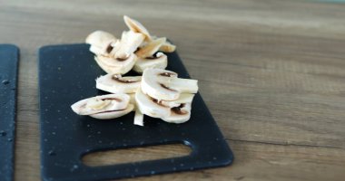 Şampiyon ve domates parçaları tam bir rota için malzeme görevi görüyor. Mutfakta yemek pişirmek için tencereli indüksiyon sobası var.