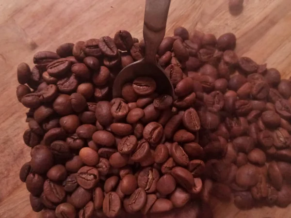 Ahşap arka planda kavrulmuş kahve çekirdekleri.