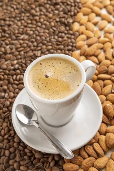cup of coffee on coffee beans and almonds top view