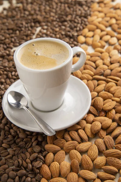 cup of coffee over coffee beans and almonds side view