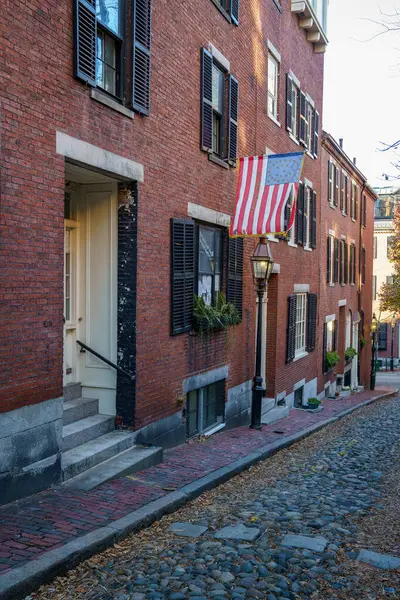 Sonbahar hasadı sırasında Boston, Massachusetts 'te Amerikan Bayrağı ve kaldırım taşı sokağındaki Acorn Street Beacon Hill evi.