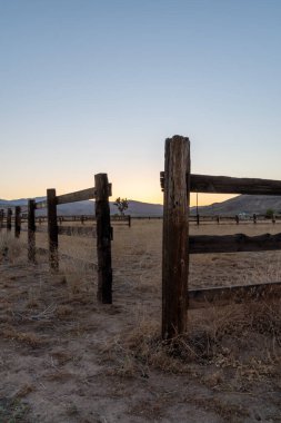 Pioneertown 'da eski bir çöl çiftliğinde eski ahşap çit. Arkasında günbatımı ve dağlar var..