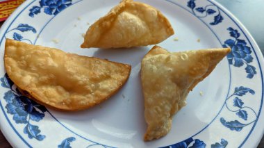 Yengeç Rangoon ve kızarmış Wonton 'lar bir Çin lokantasında mavi nilüfer desenli beyaz bir tabakta servis edilir..