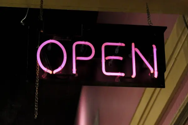 Bir iş penceresinde asılı pembe neonlu açık tabela