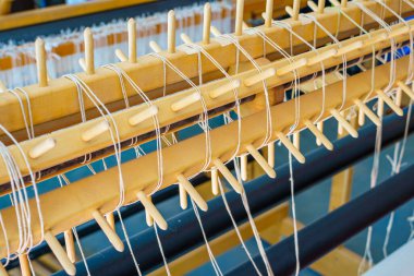 Bir zemin tezgahının yakın çekimi. Ahşap mandallı bölümlü warp silindiri.