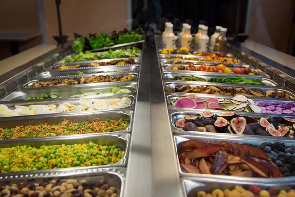 Food and salad bar with a large variety of fruits, vegetables, and dressings