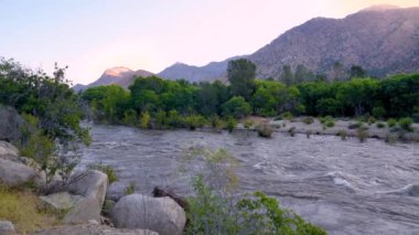 Kernville Nehri, 2023 'te eriyen kar ve yağmurlar nedeniyle ağır biçimde suyla doludur. Sabahın erken saatlerinde Kernville, California 'da arka planda dağlarla çekilmiş..